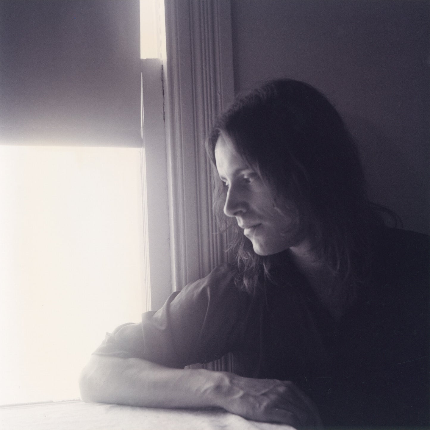 Black and white portrait of a man looking out a window.