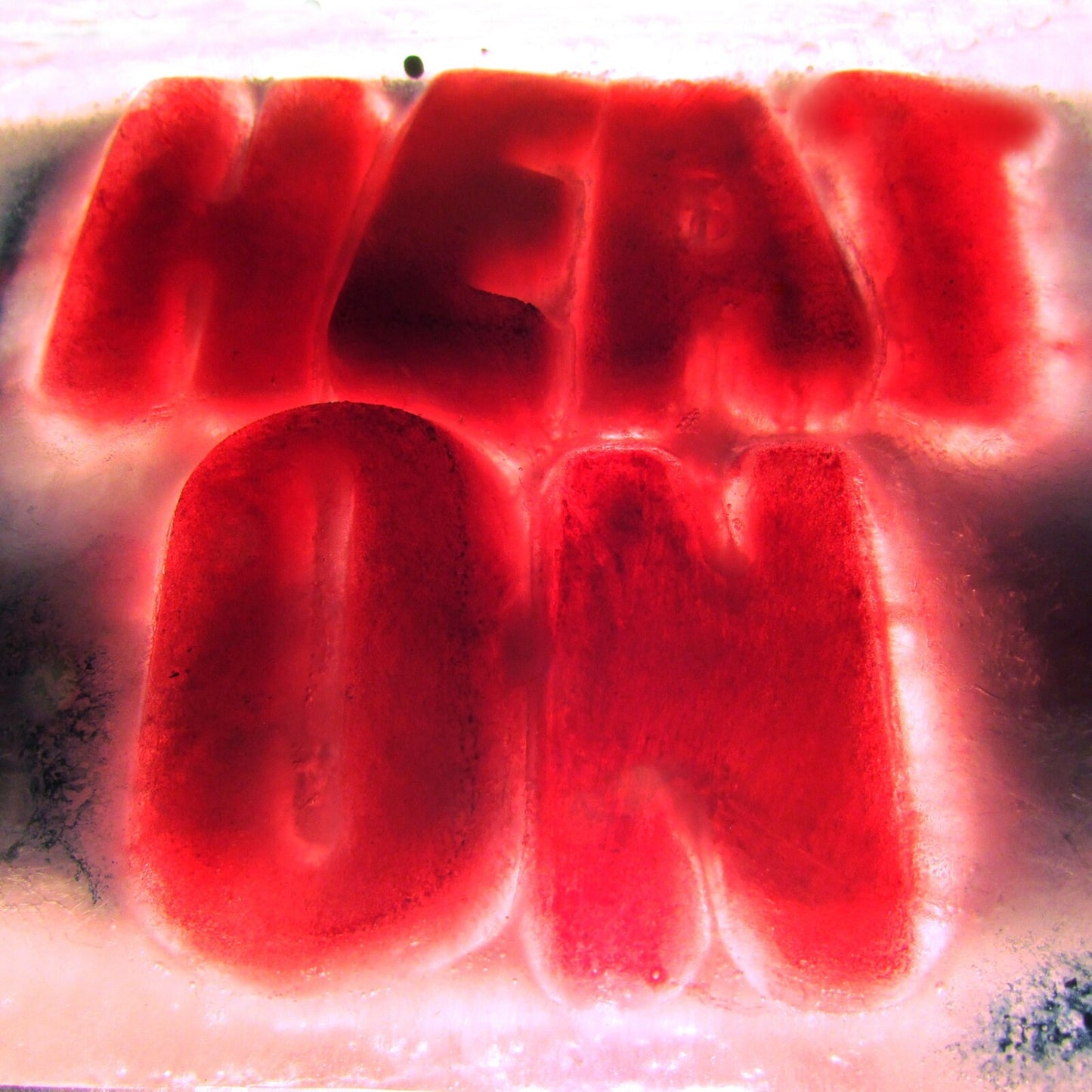 Close-up of a red CD with the words "HEAT ON" embossed on it.