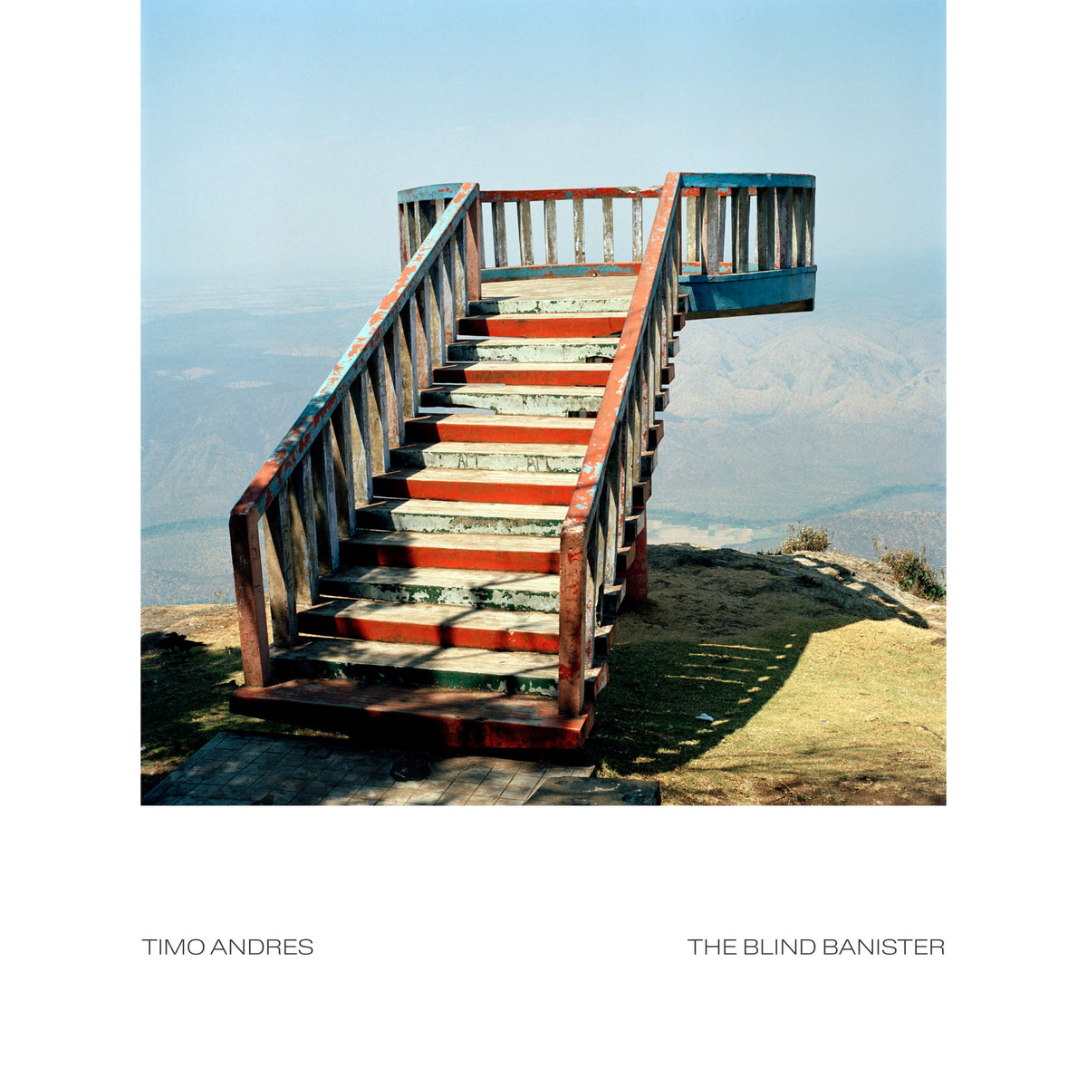 Painted wooden staircase leading upwards towards a hazy mountainous landscape.