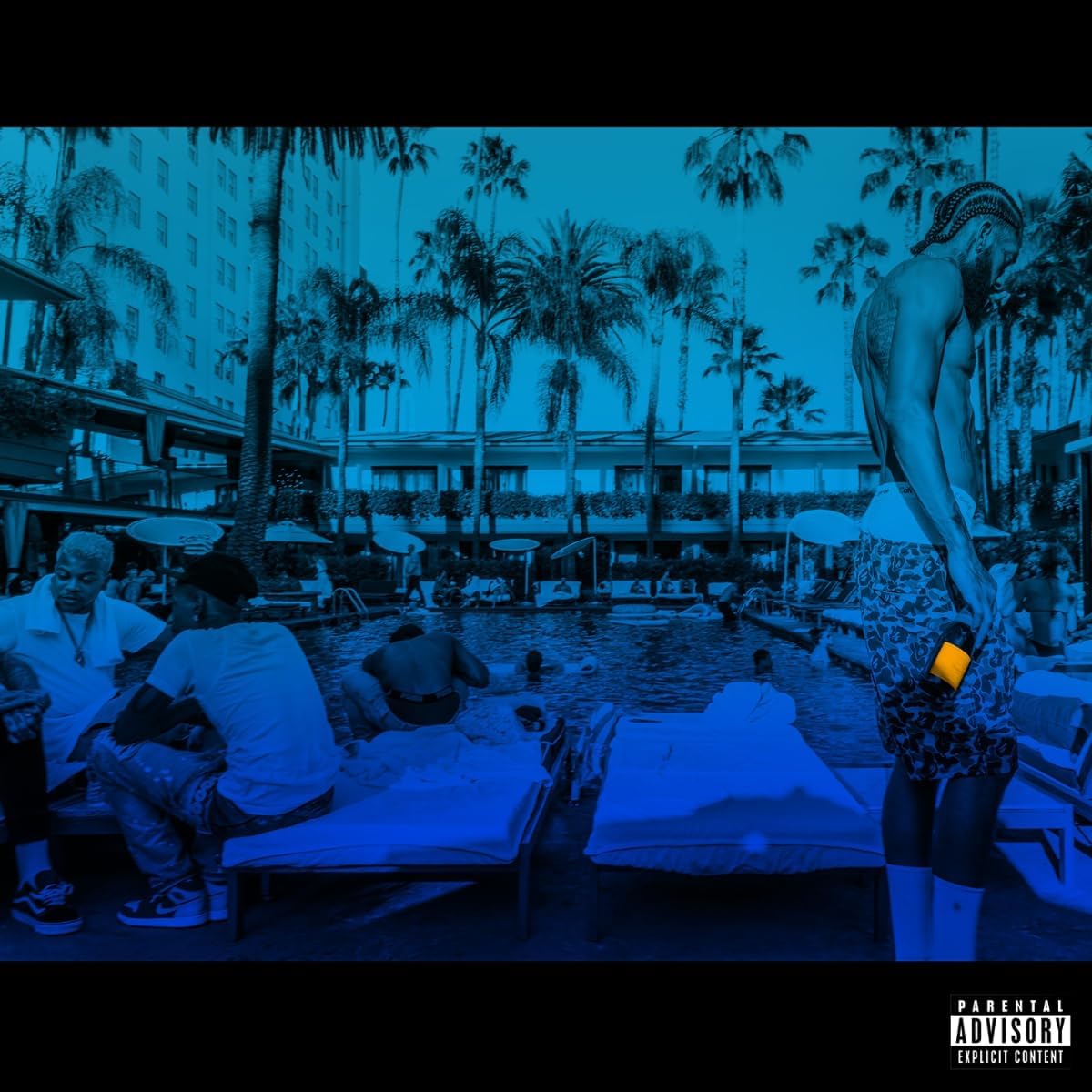 Blue-tinted image of people at a resort pool with palm trees and buildings.