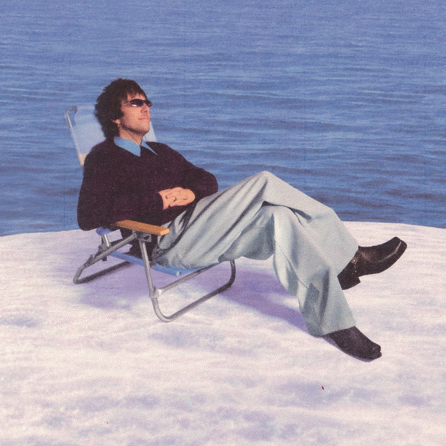 Man in sunglasses relaxing in a deck chair by the water.