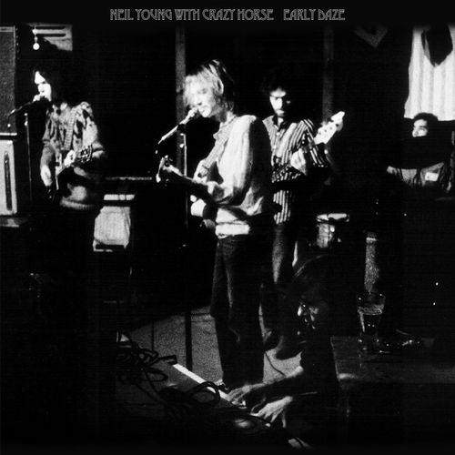 Black and white photo of Neil Young with Crazy Horse performing onstage.