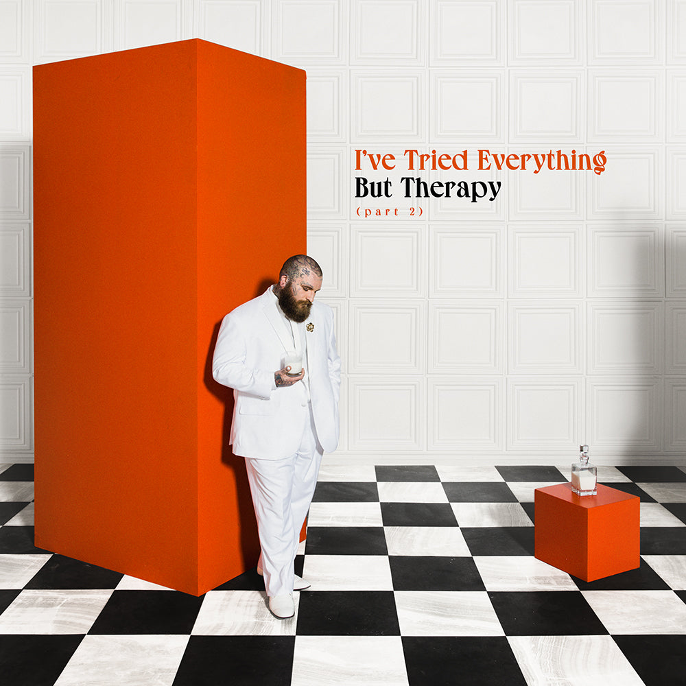 Teddy Swims in a white suit leans against a red geometric structure.