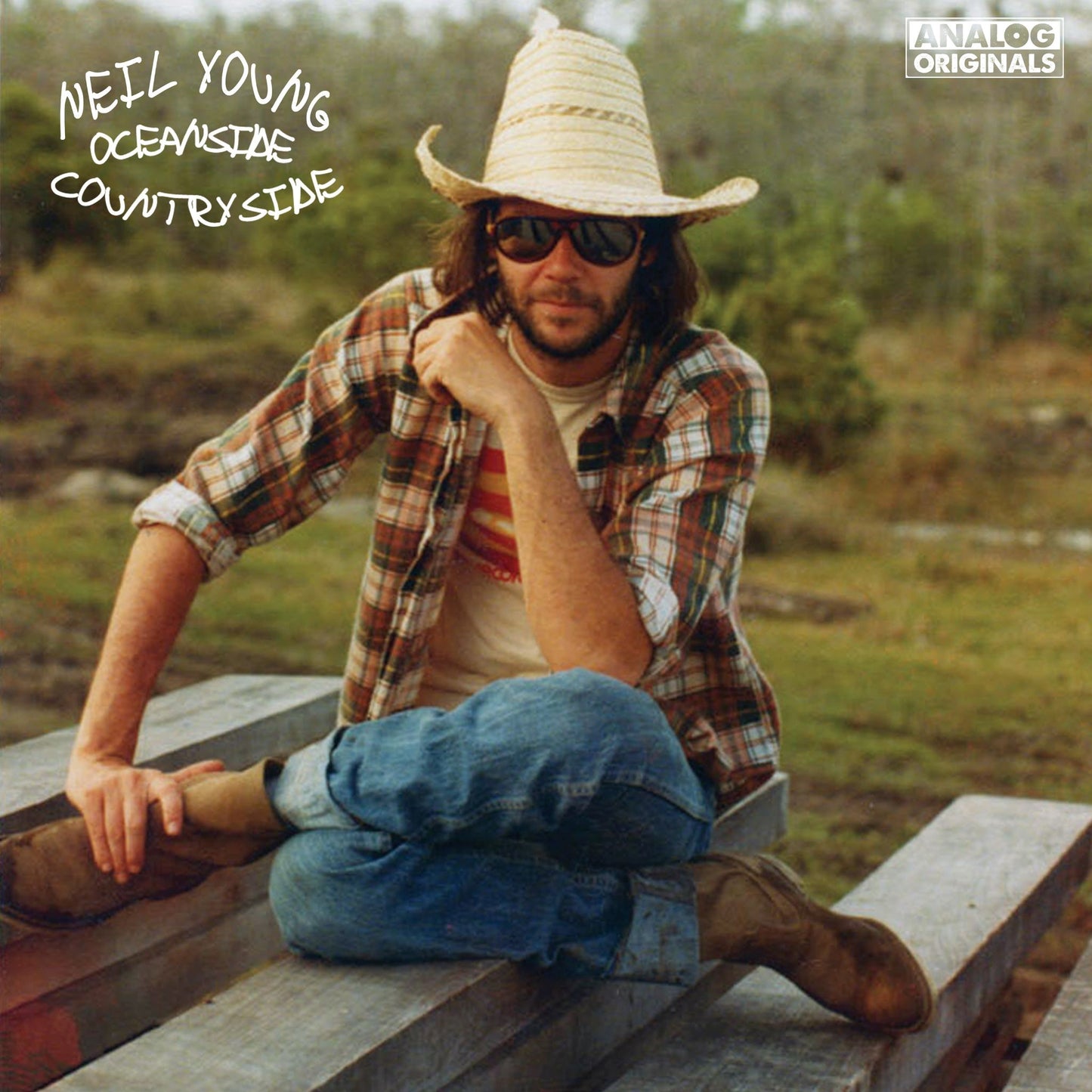 Neil Young album cover: man in a straw hat sits on wood.