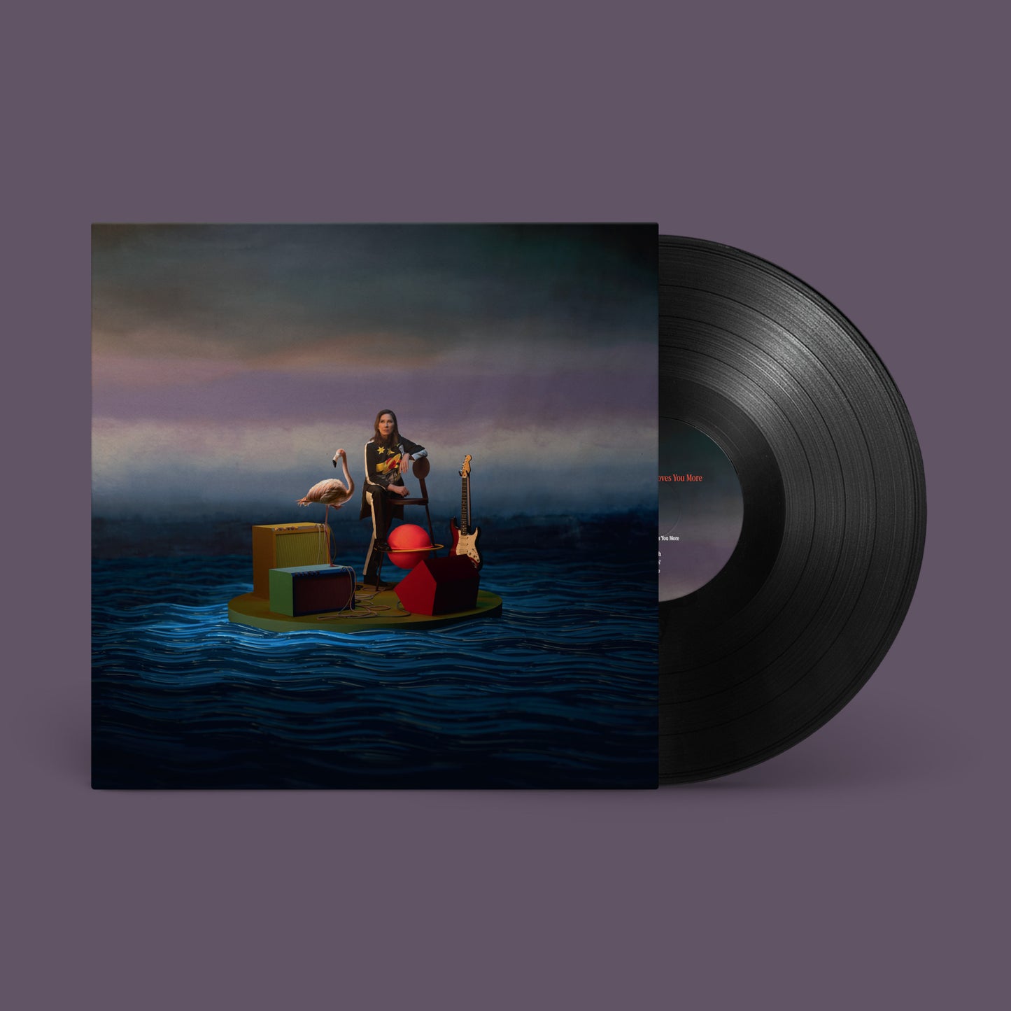 Kim Deal sitting on a floating platform with a flamingo, guitar, and amplifiers.