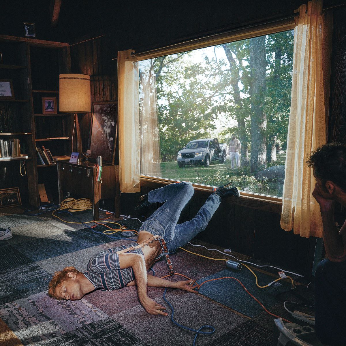 A person lies on the floor with legs raised against a window in a room.
