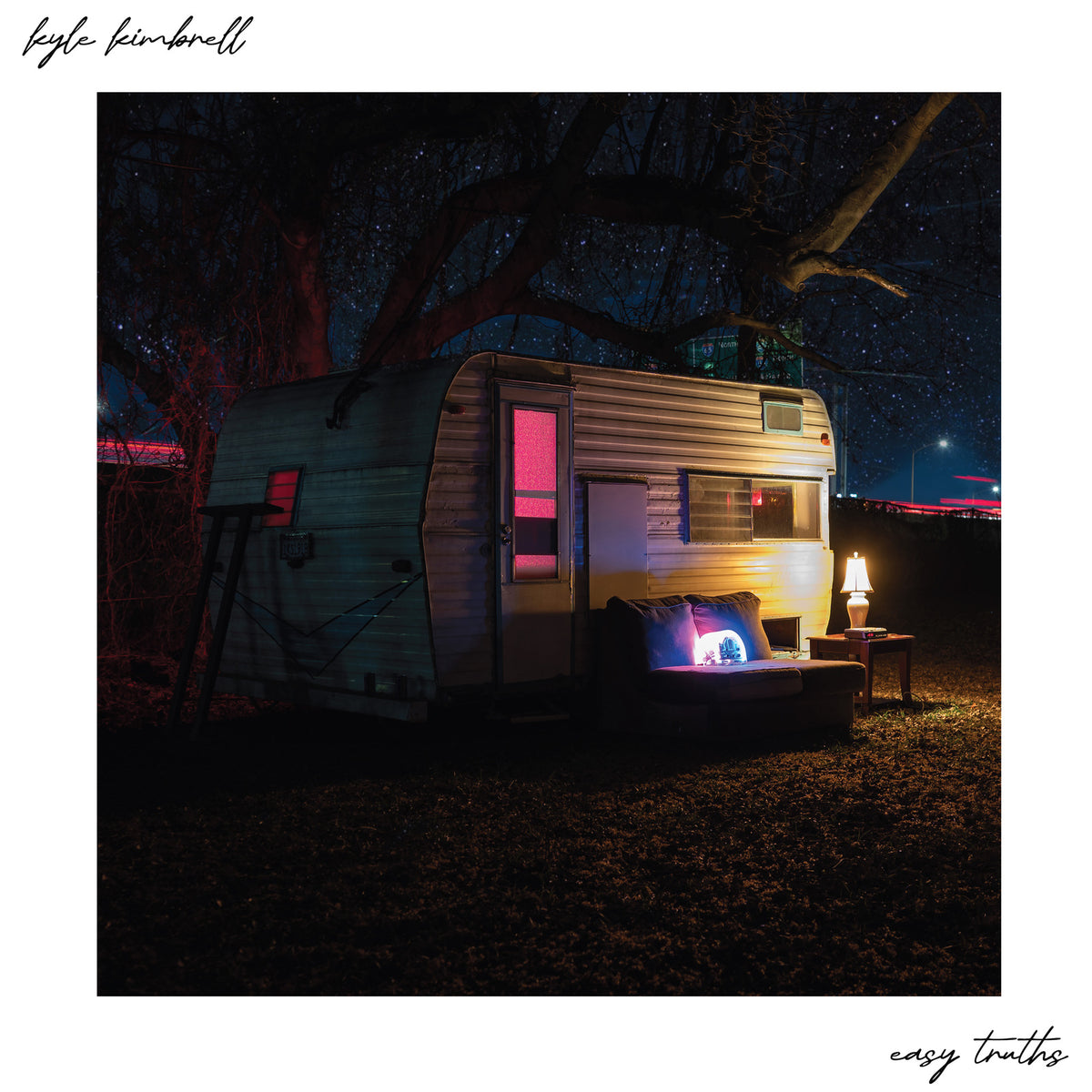 Vintage trailer at night with illuminated windows and surrounding trees.