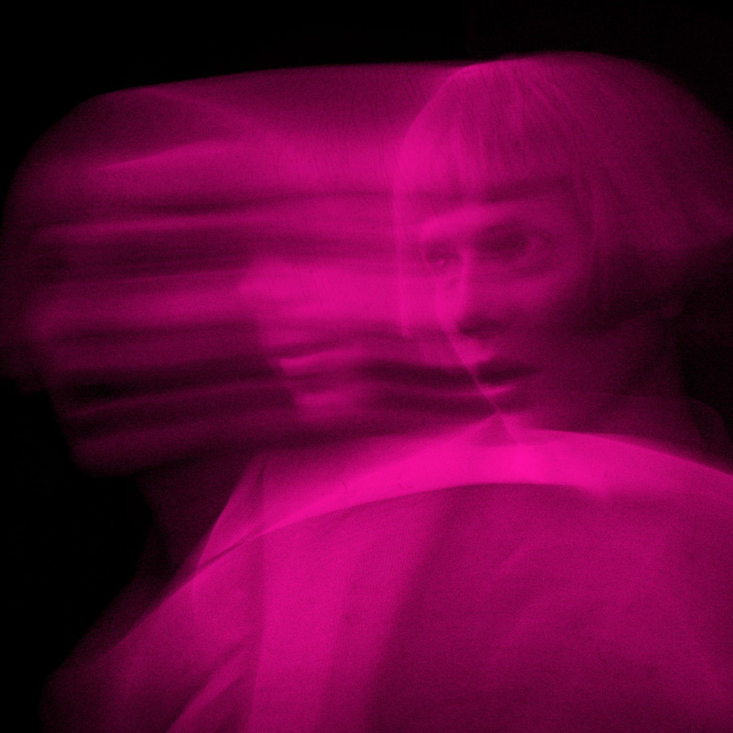 Blurred pink portrait of a person with short hair, looking forward.