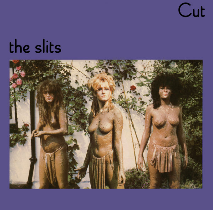 Three women covered in mud stand before a rose bush on a purple background.
