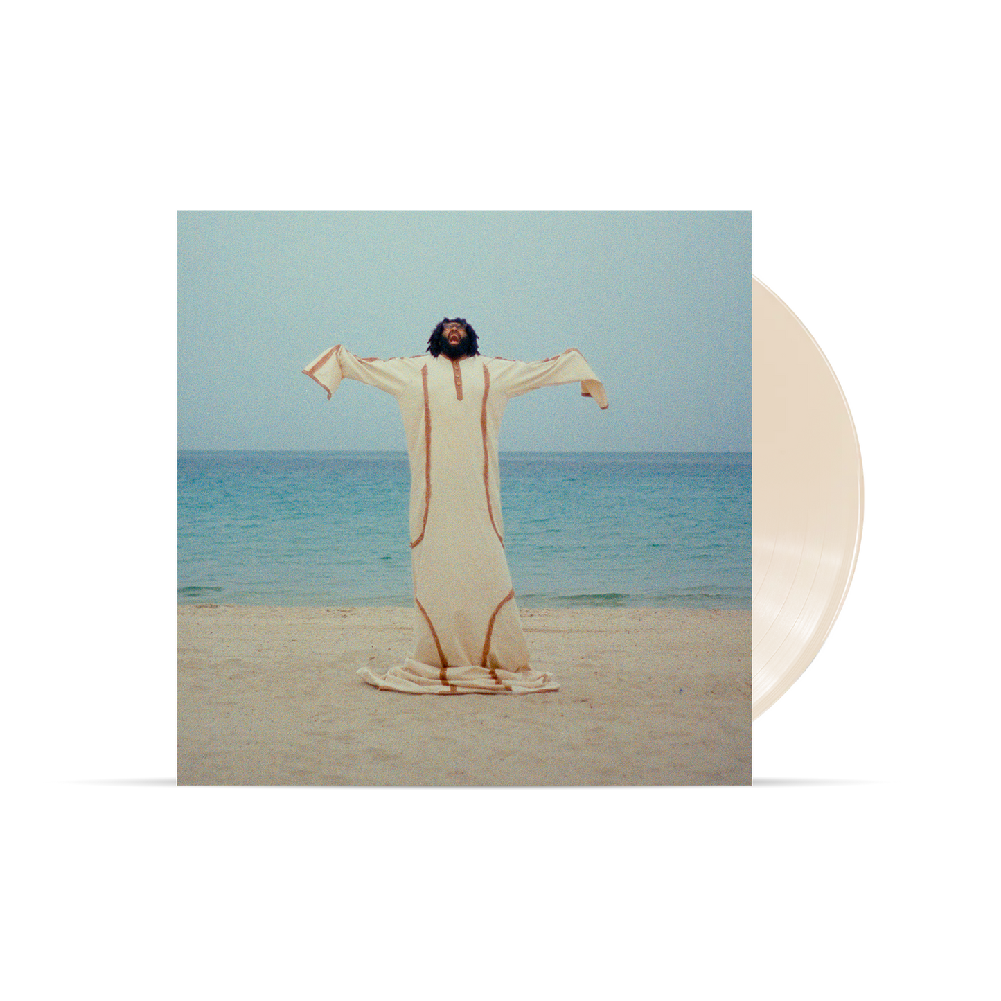 Man in beige robe with arms outstretched on a sandy beach.