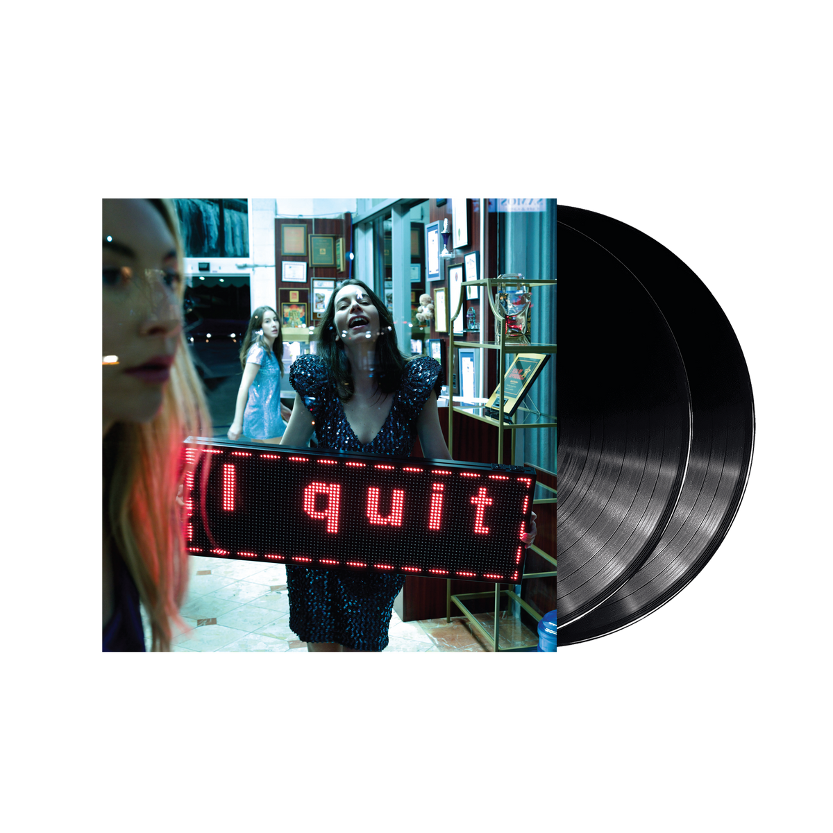 HAIM album cover with a woman holding a lit “I quit” sign and vinyl record.