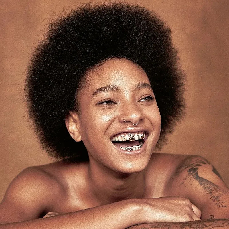 Smiling young Black woman with an afro and grill jewelry.