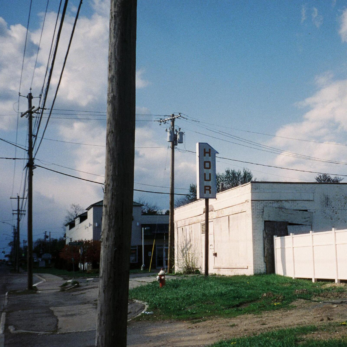 Street scene with a tall "HOUR" sign and white buildings under a blue sky.