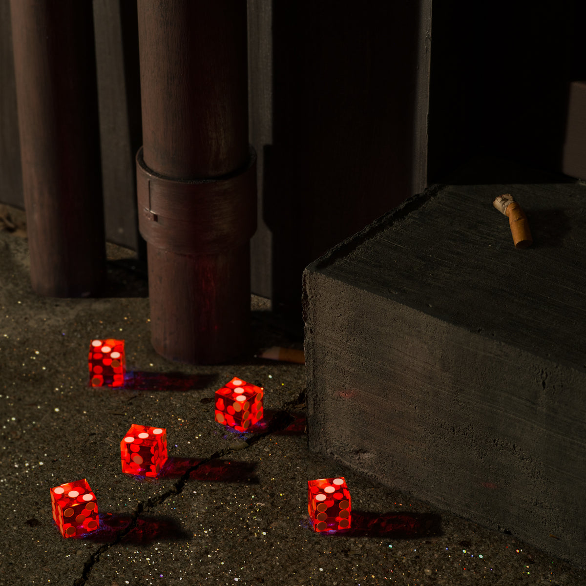 Red dice showing threes scattered on a cracked concrete floor.
