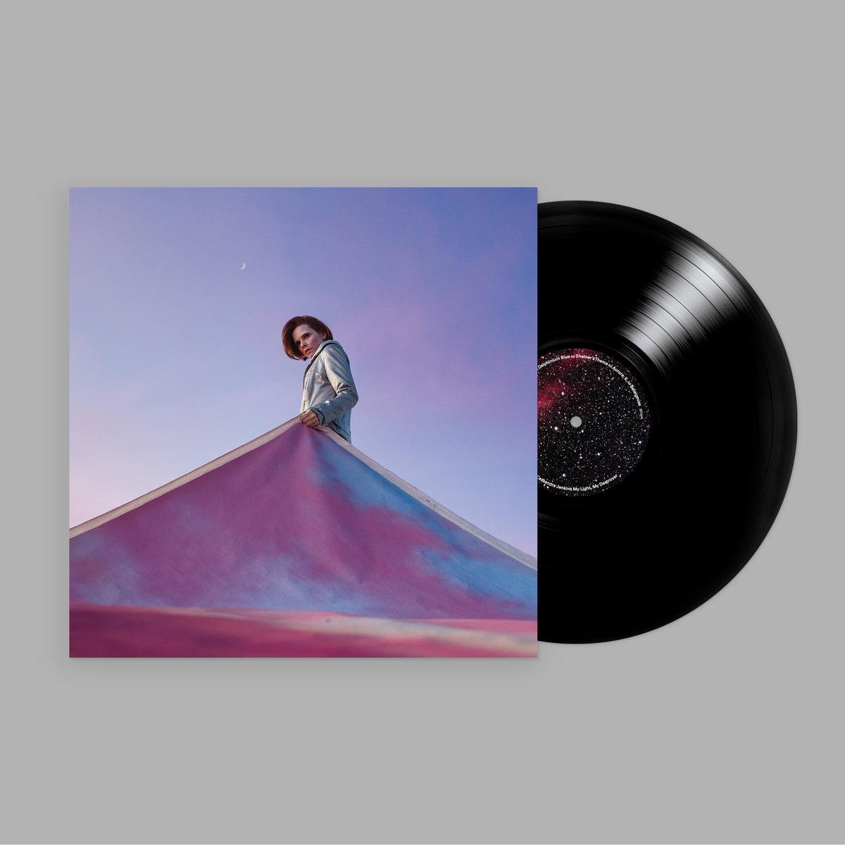 Vinyl record and album cover featuring a person on a colorful hill.