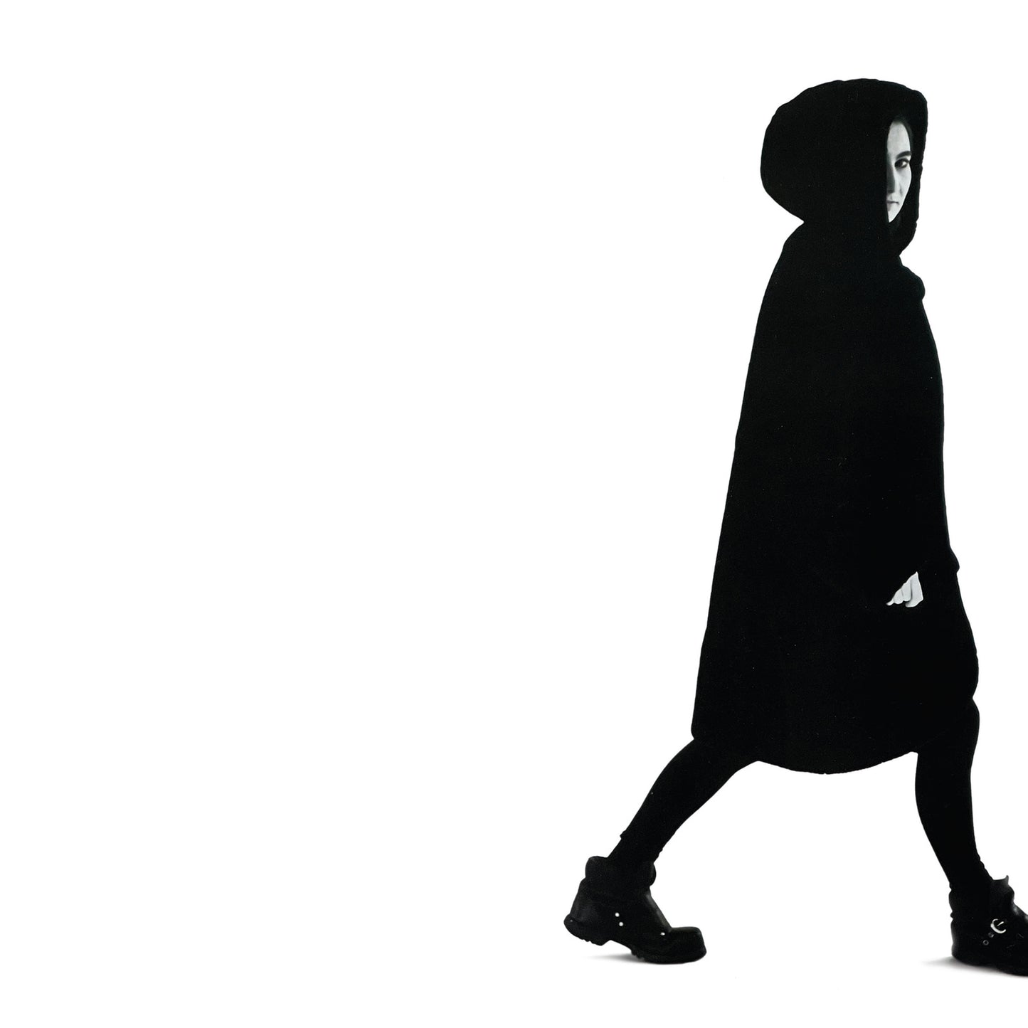 Black and white image of a person in a hooded cloak walking.