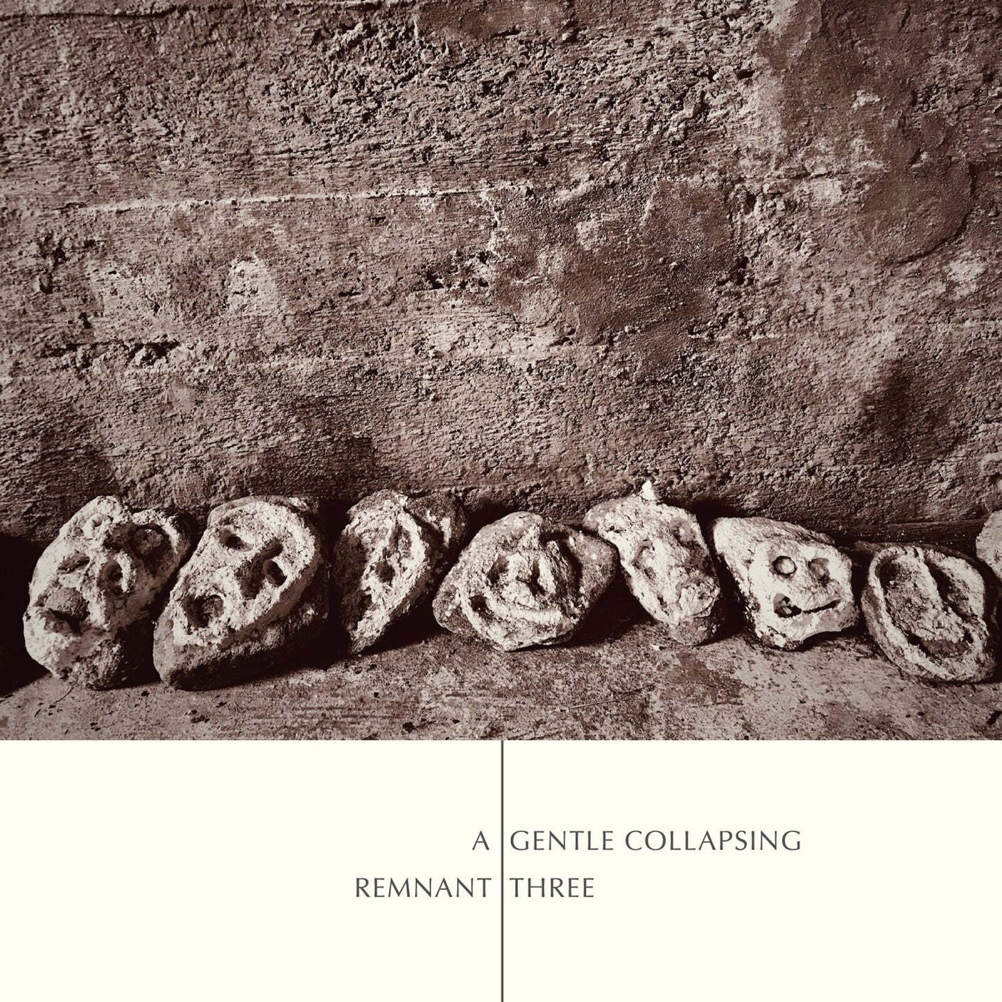 CD cover with a row of weathered stone heads against a textured wall.