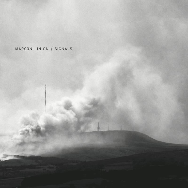 Black and white image of a hill with radio towers and billowing smoke.