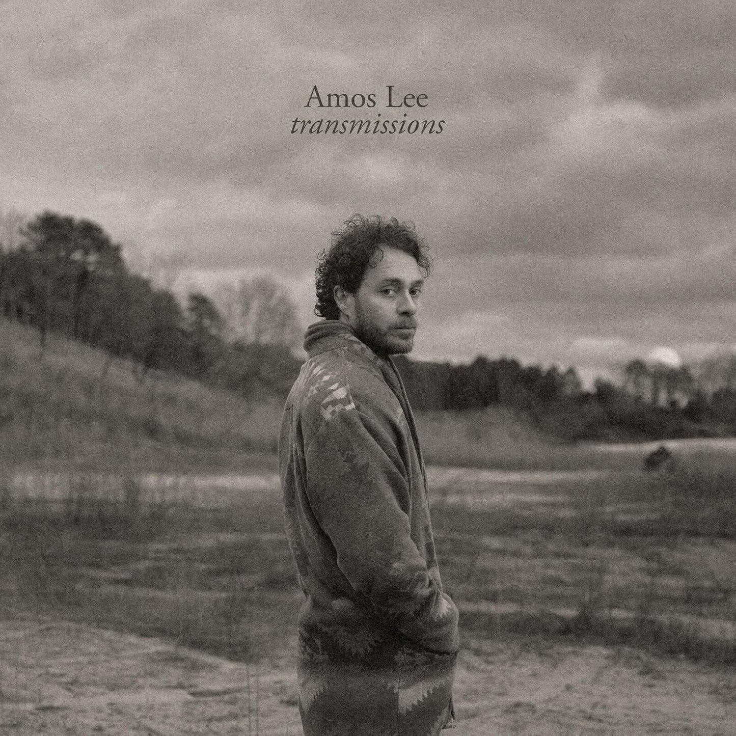 Black and white album cover featuring Amos Lee in a field.