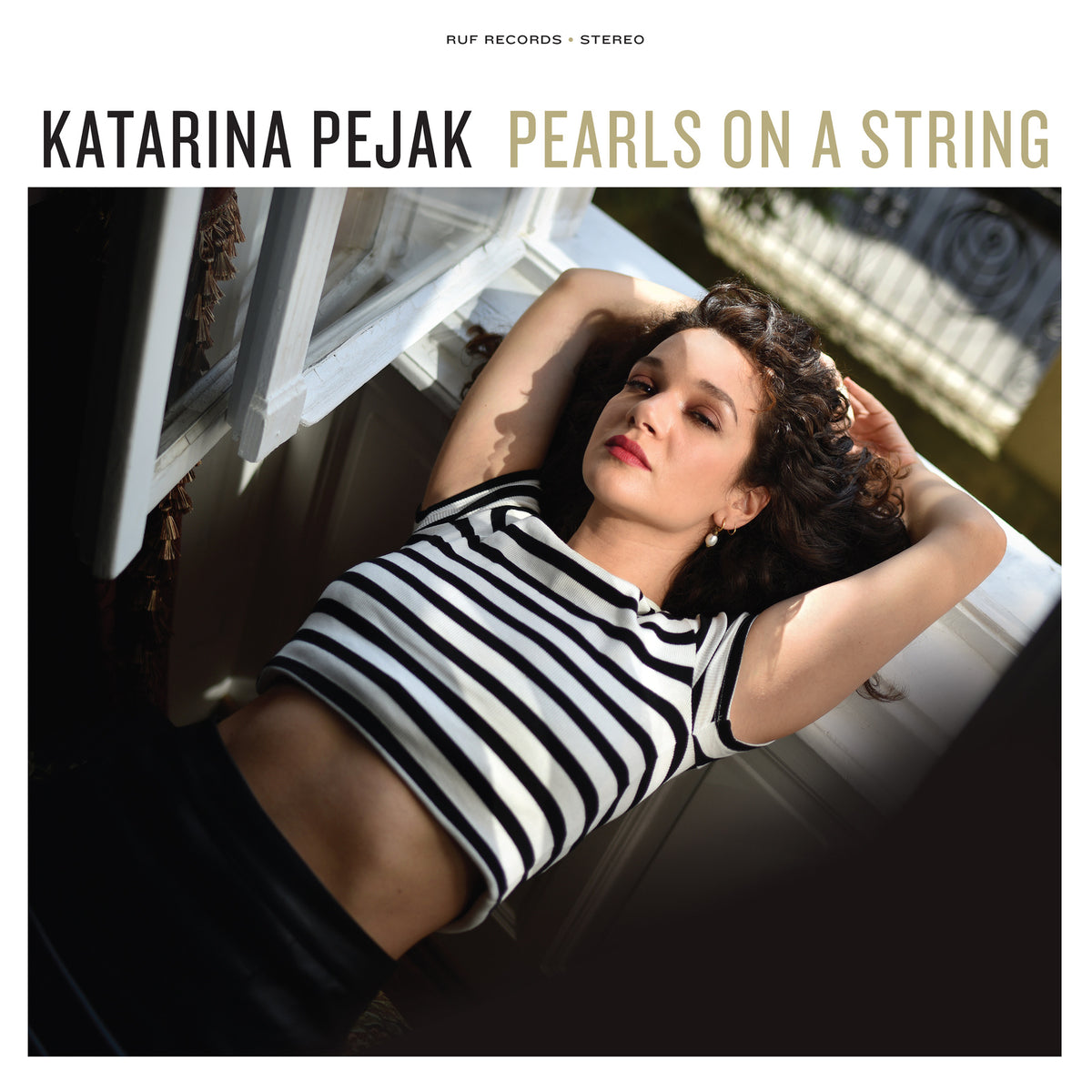 Album cover: woman lying by a window, striped shirt, sunlight.