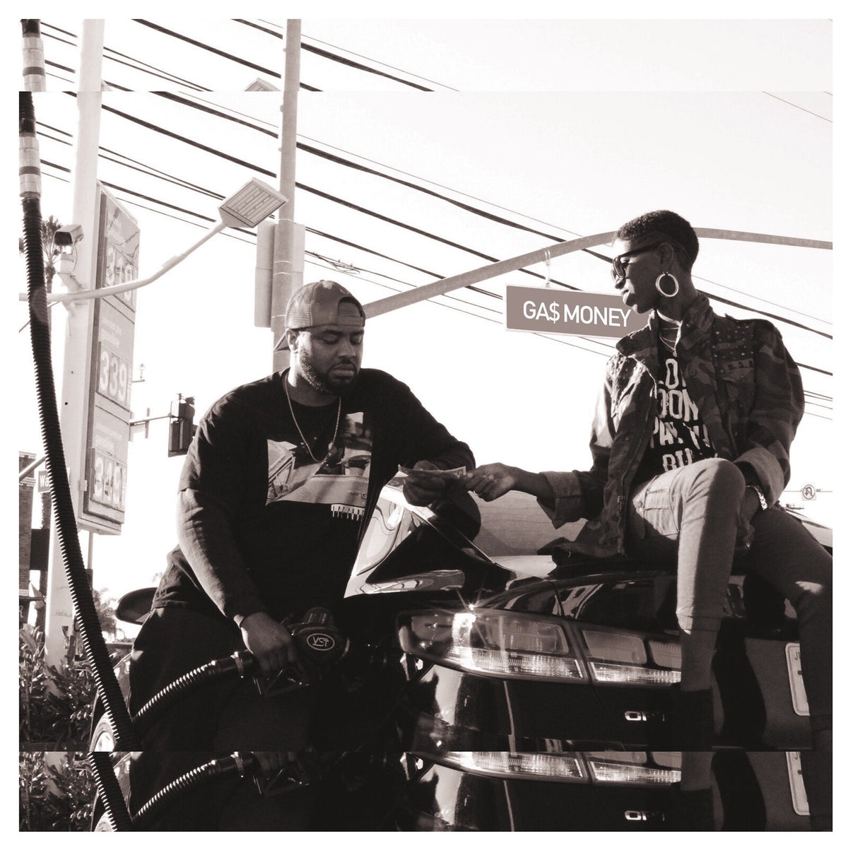 Black and white photo of two men at a gas station with a motorcycle.