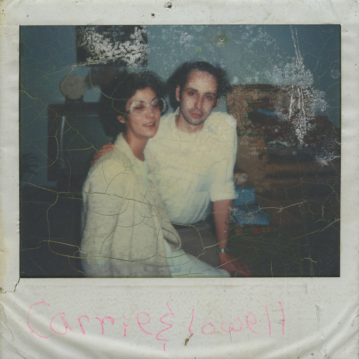 Cracked photo of a woman and man embracing, with handwritten text below.