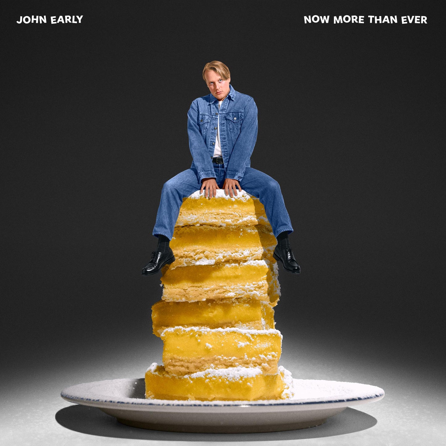 John Early sits atop a tall stack of lemon bars on a white plate.