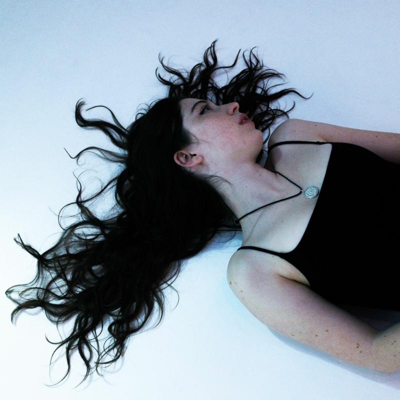 Woman with long dark hair lying down, album cover art.