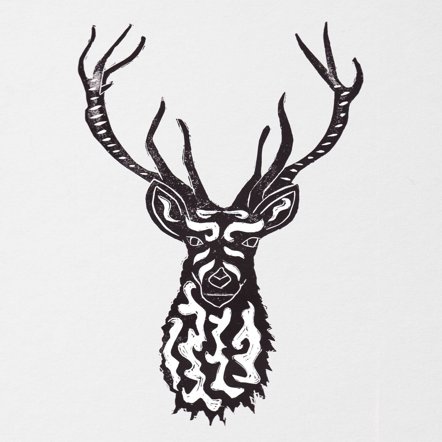 Black and white linocut print of a stylized deer head with intricate patterns.