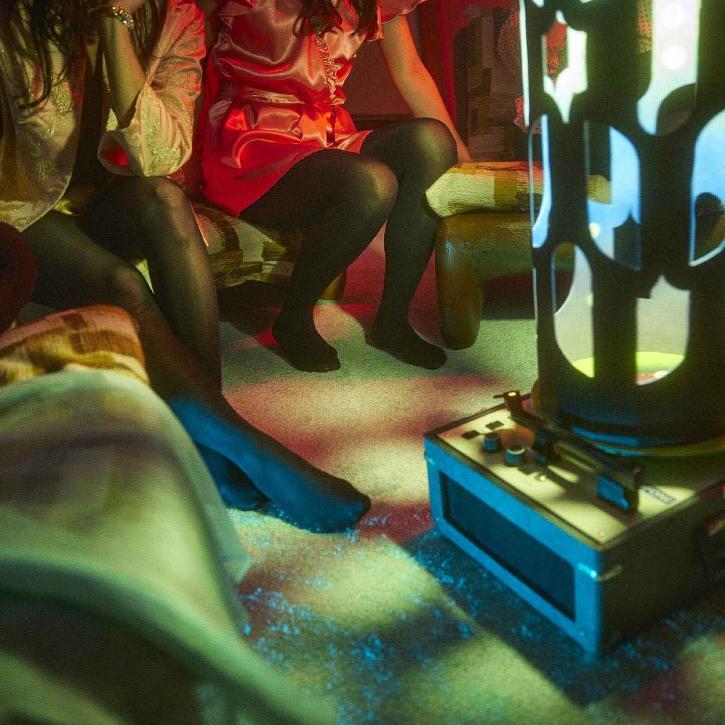People in a dimly lit room with a record player and projected light.