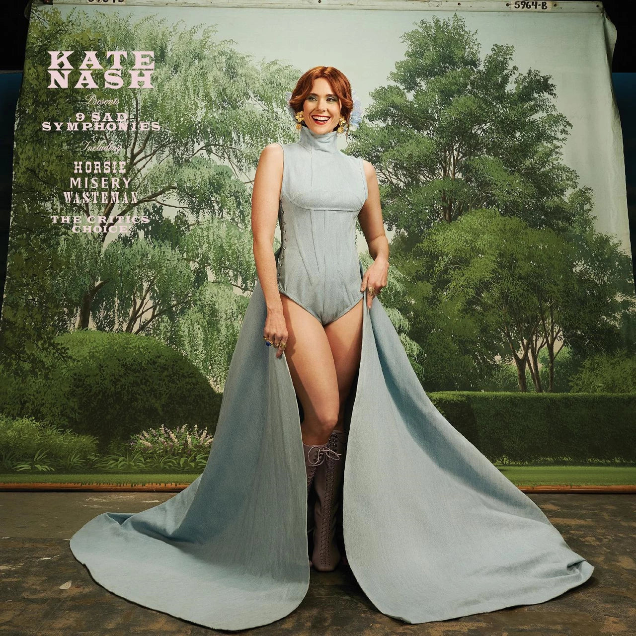 Kate Nash album cover: artist in a blue gown amidst trees.