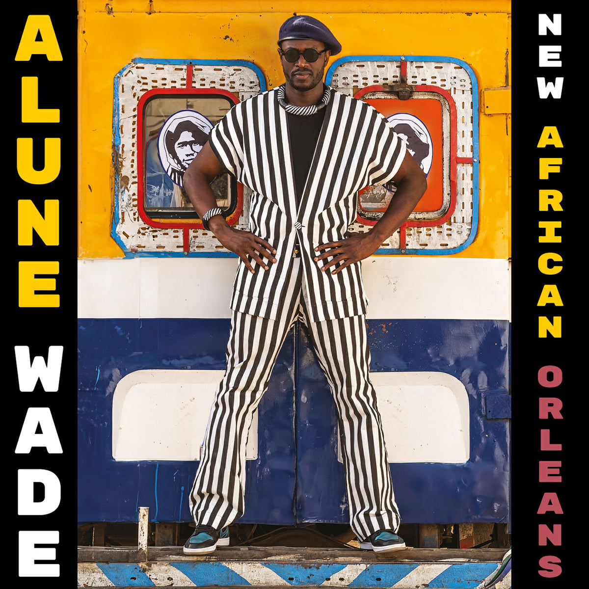 Alune Wade album cover: man in striped suit before colorful wall.