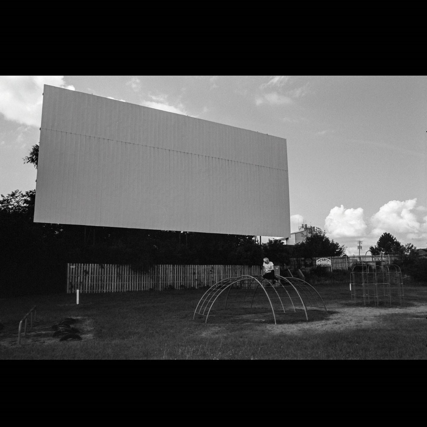 Black and white photo of a drive-in movie screen and playground.