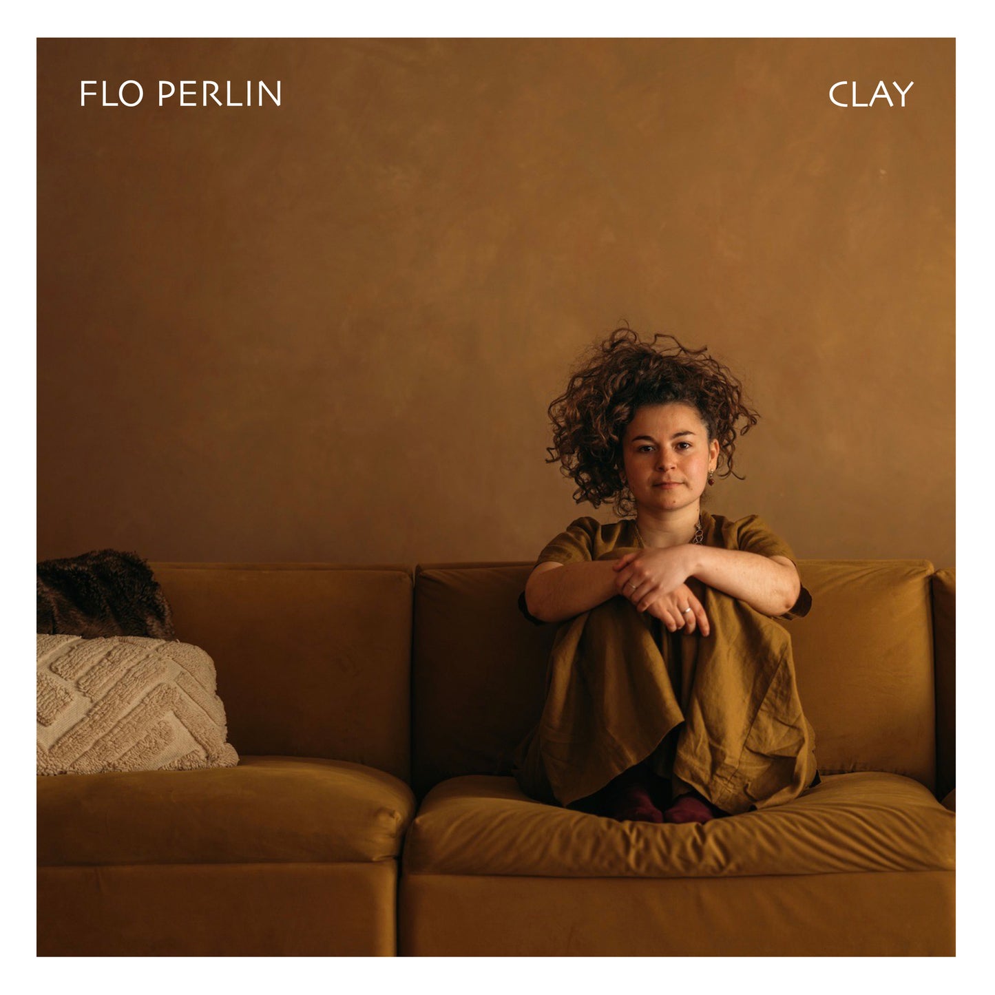 CD cover: Woman with curly hair sitting on a brown couch.