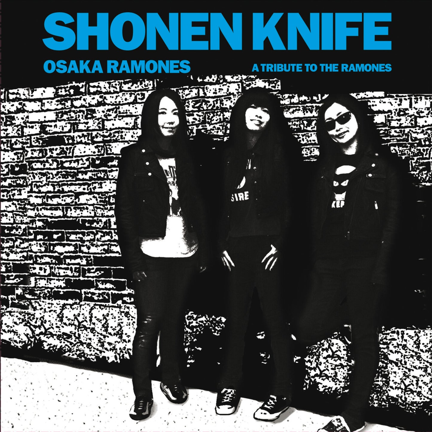 Black and white album cover featuring four figures in front of a brick wall.
