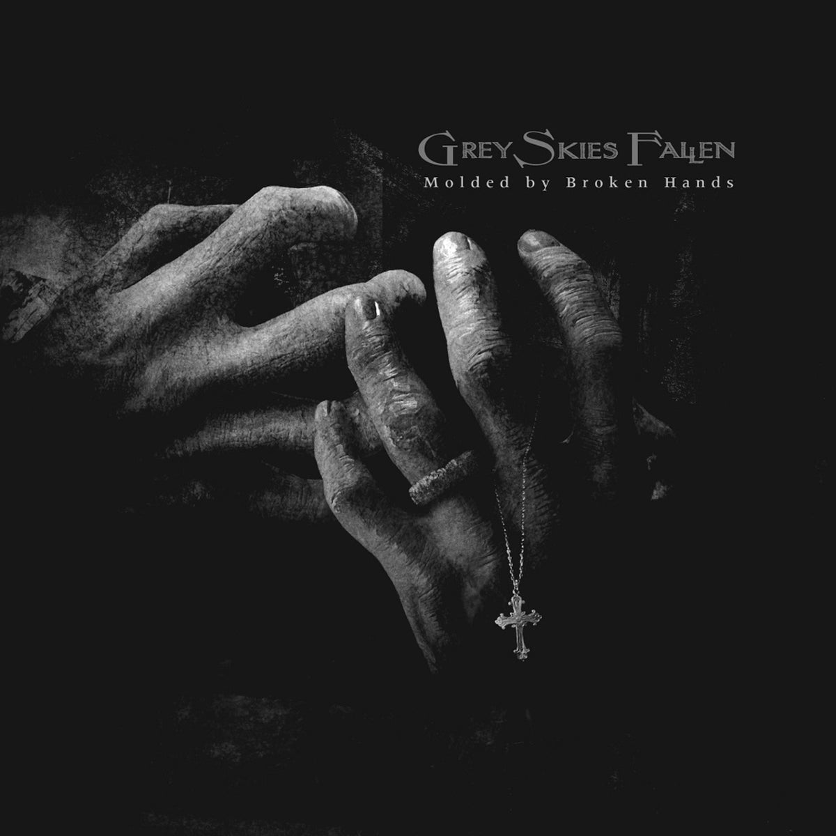 Black and white image of hands holding a necklace with a cross.