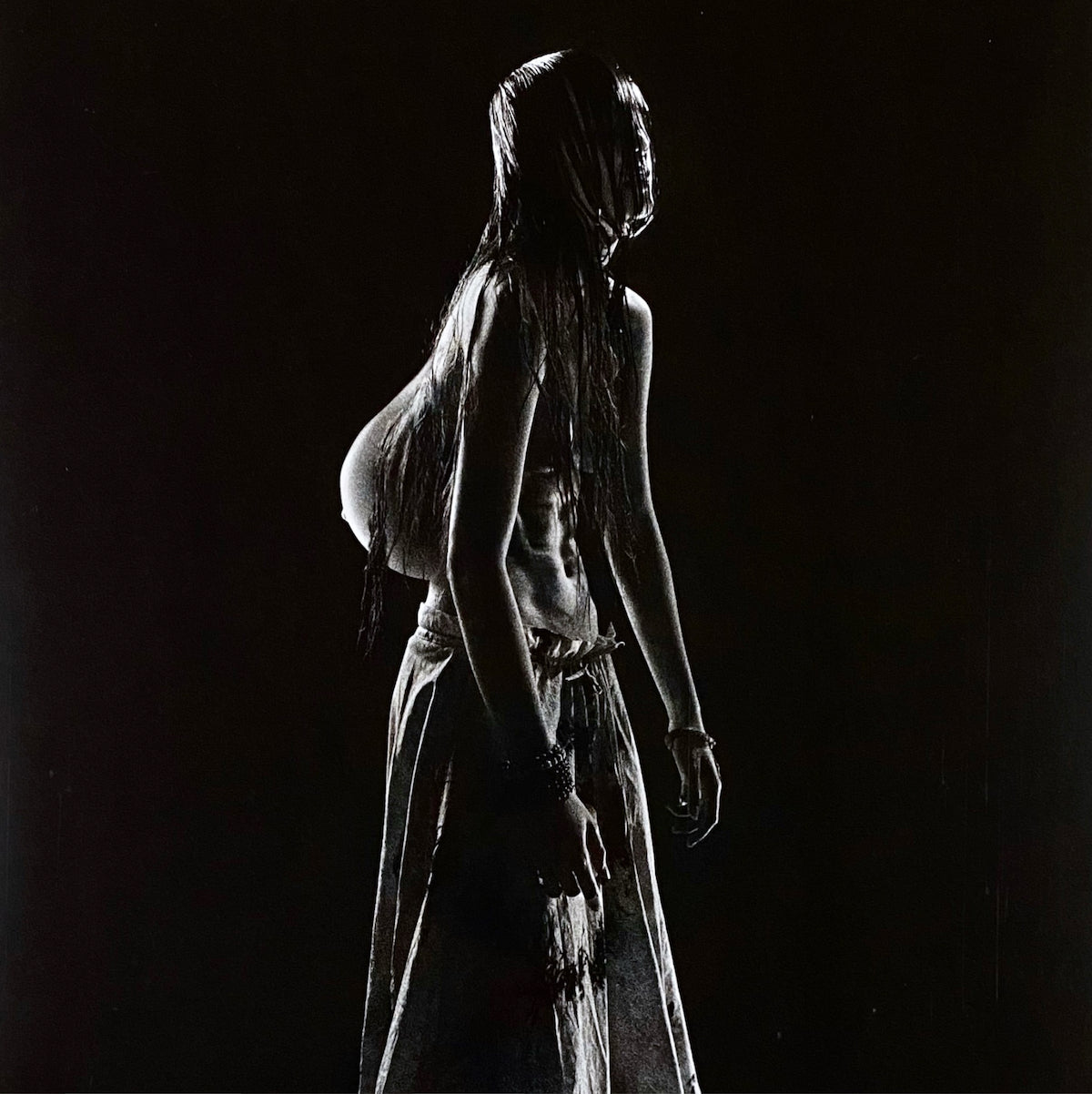 Dark, artistic portrait of a woman with long hair, facing away.