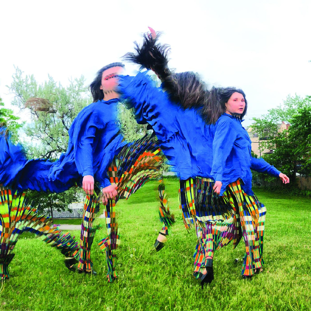 Woman in blue shirt and patterned pants, duplicated in motion outdoors.