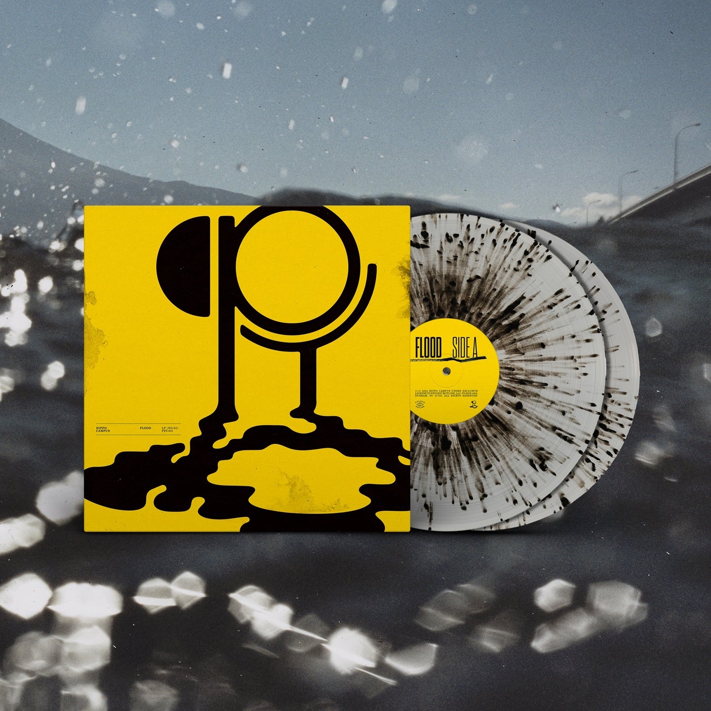 Yellow album cover with black dripping logo next to a black-splattered clear vinyl record.