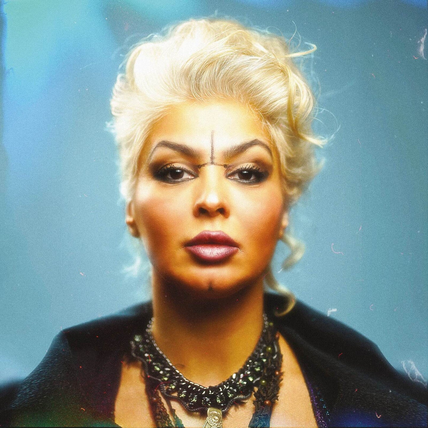 Portrait of a woman with blonde curly hair and dark facial markings.