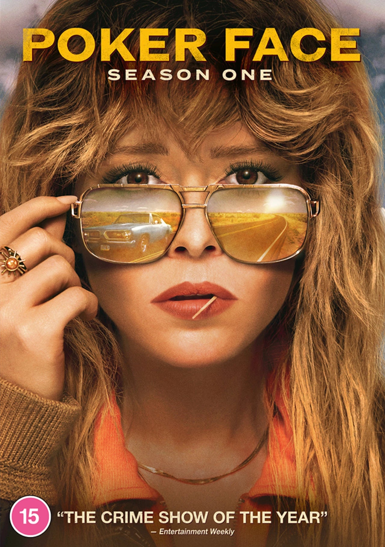 Close-up of a woman wearing sunglasses reflecting a car on a desert road.