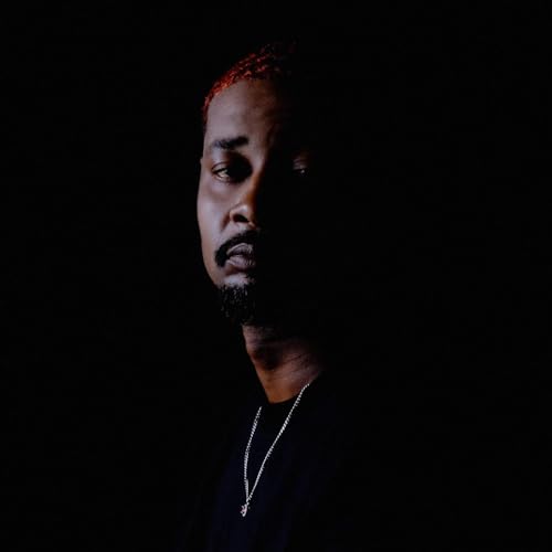 Portrait of Danny Brown with red hair, looking off to the side.
