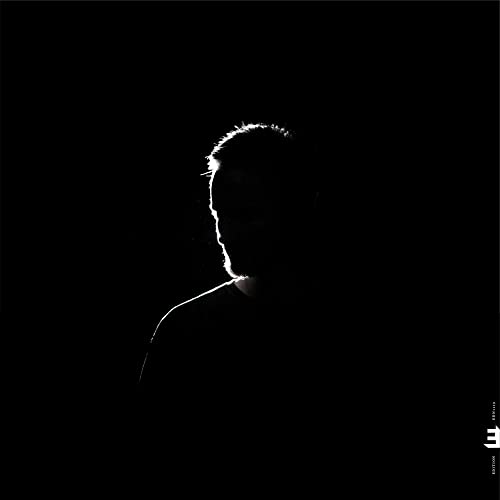 Black and white portrait of a man’s face in shadow, CD cover.