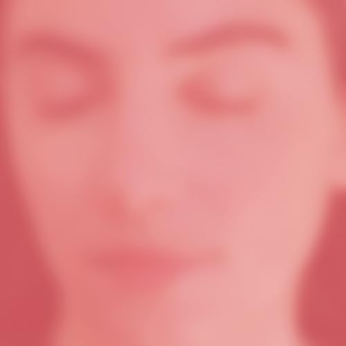 Blurred close-up of a woman’s face on a reddish background.