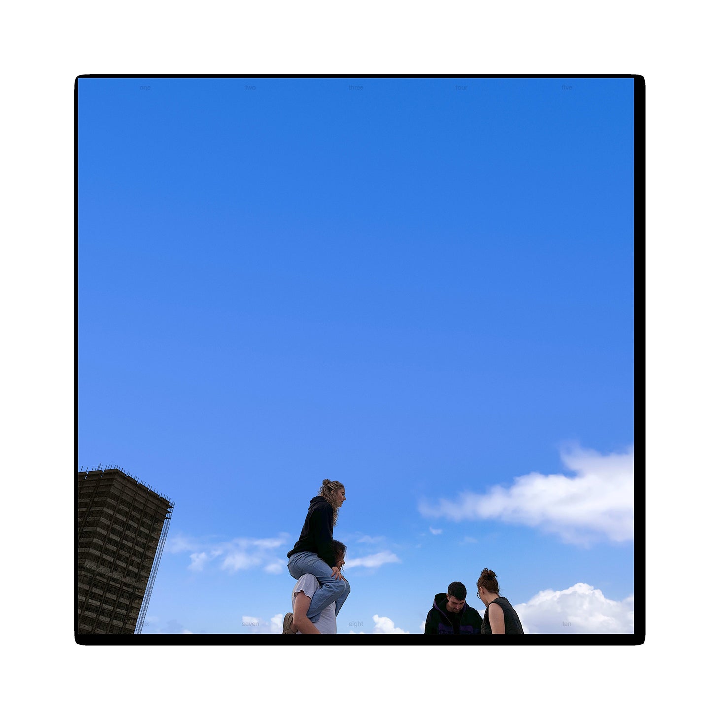 Blue sky with figures silhouetted against a building and clouds.