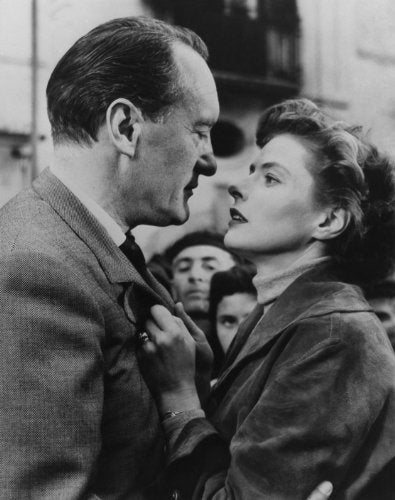 Black and white film still of a man and woman in a tense embrace.