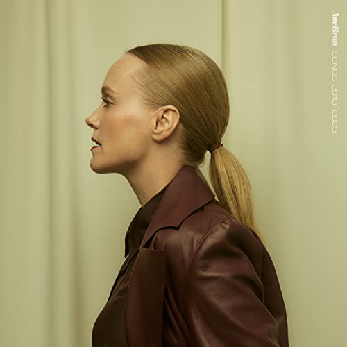 Side profile of a blonde woman in a burgundy jacket.