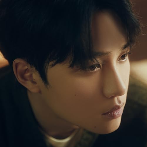 Close-up portrait of a young man with dark hair, looking downward.
