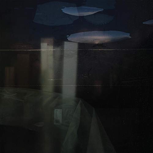 Dark abstract album cover with blurred shapes and light streaks.