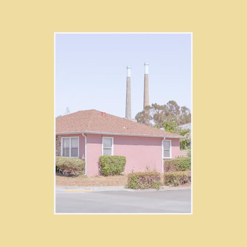 Pink building with a red roof and smokestacks in the background.